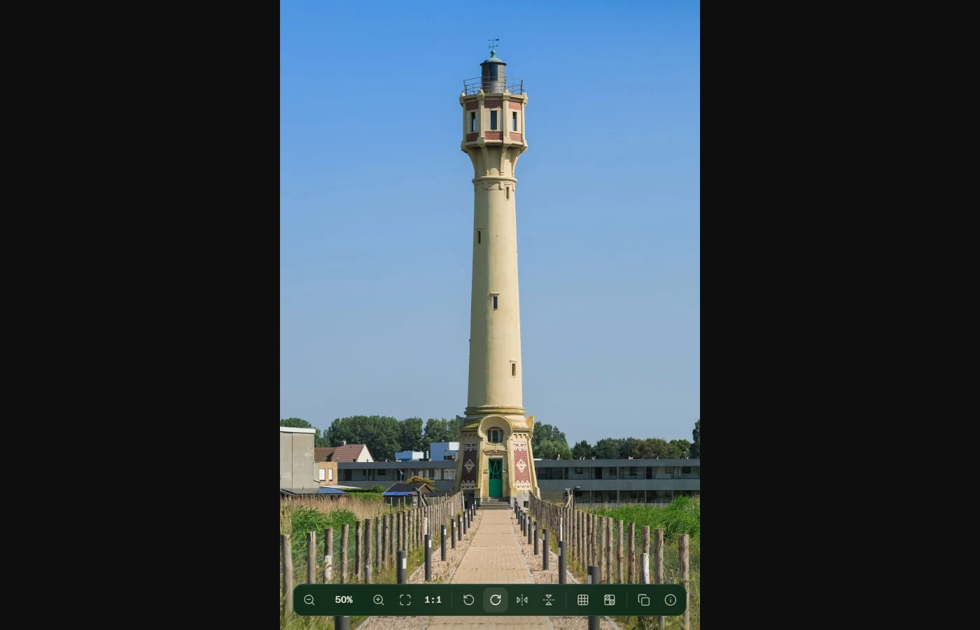 A tall lighthouse photo turned upright in Bellevue's viewer, with the toolbar along the bottom edge and its Rotate clockwise button highlighted